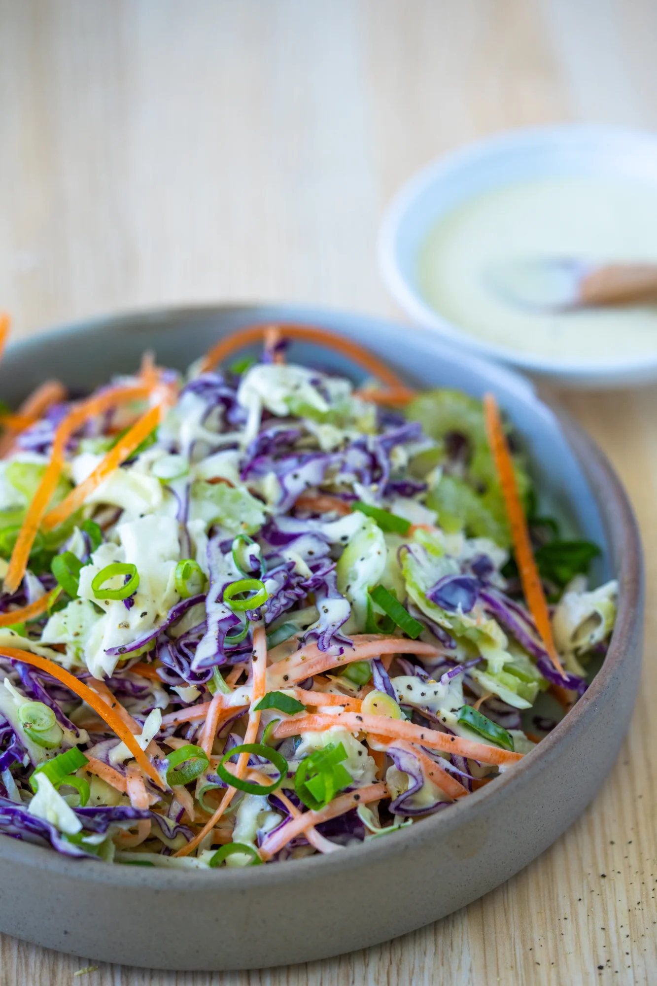 coleslaw in bowl with extra dressing on the side