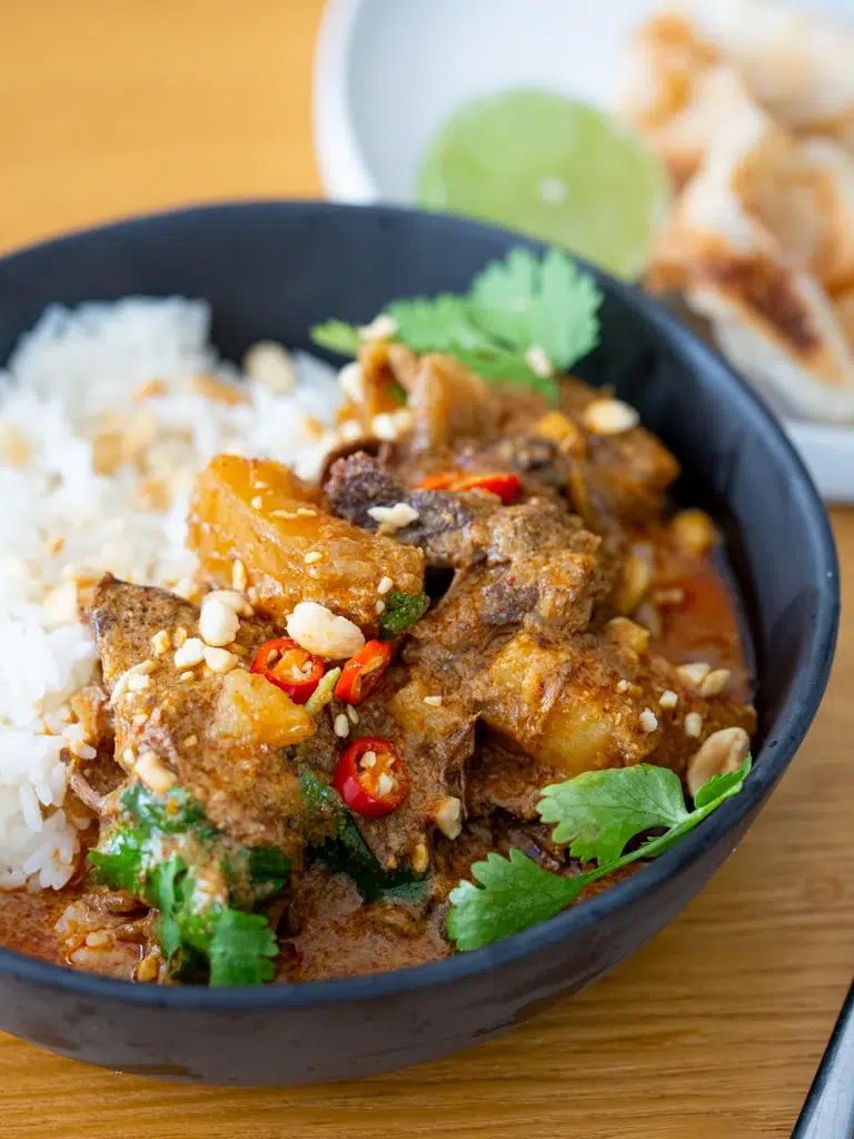 Side view of Massaman beef curry plated with rice in a bowl