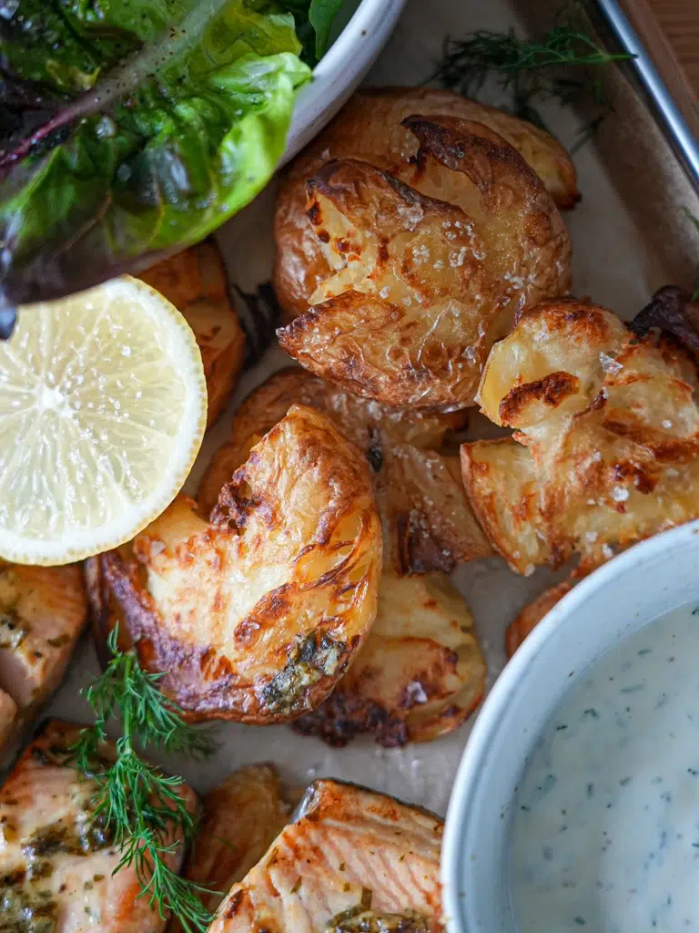 Close-up shot of golden roasted potatoes, garnished with herbs