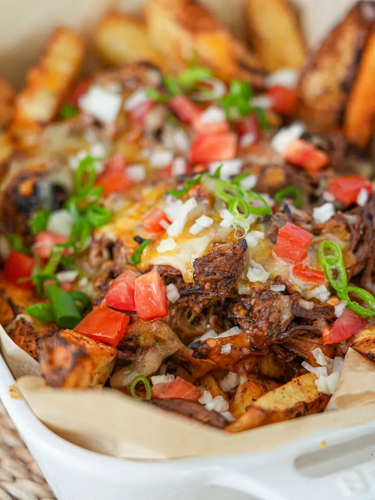 Close-up of loaded fries with beef brisket, cheese, and toppings, creating a hearty dish.