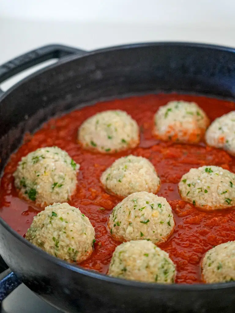 Freshly made meatballs in a pan of tomato sauce