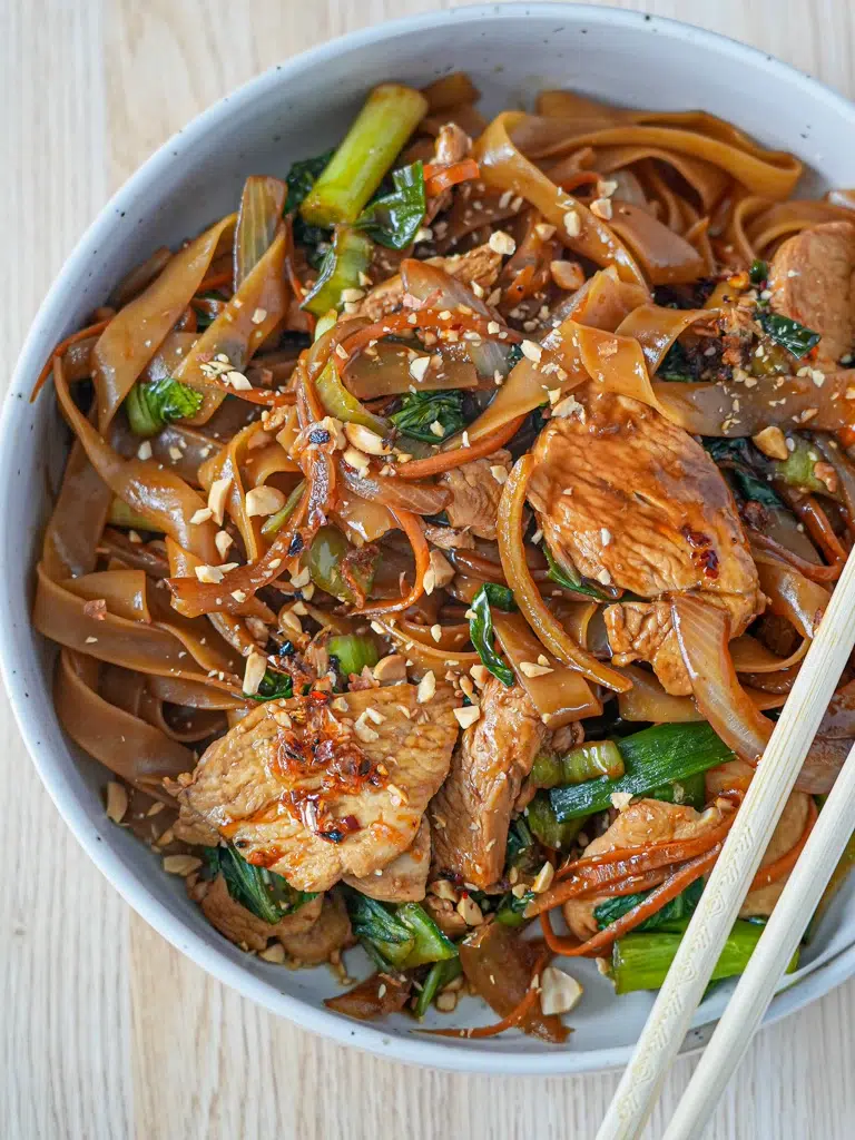 Close-up of Drunken Noodles with chopsticks resting on top