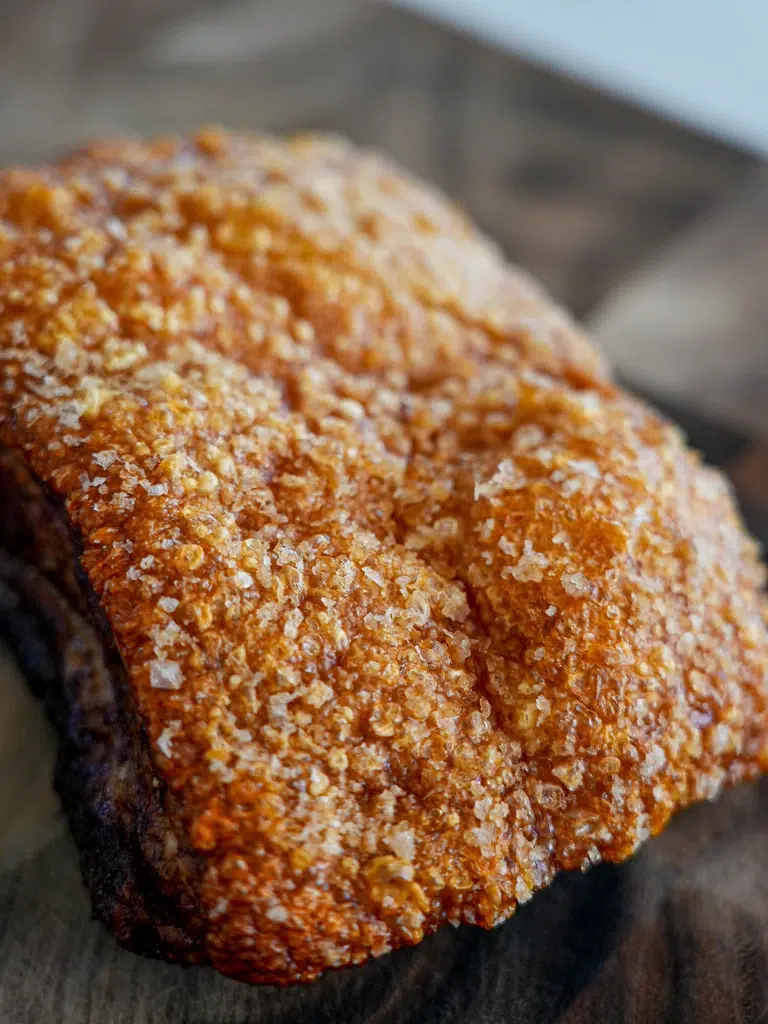 Close-up of unsliced pork crackling with crispy golden skin.