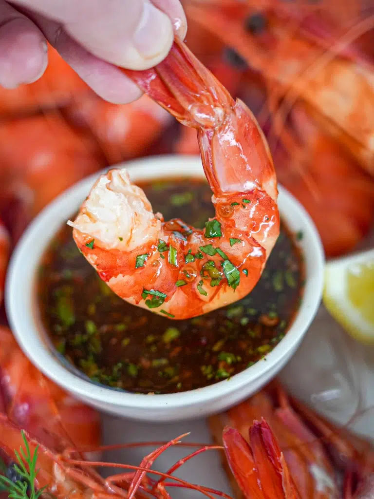 Prawn being dipped into Sweet Chilli Lime Sauce, highlighting the creamy and flavorful texture.