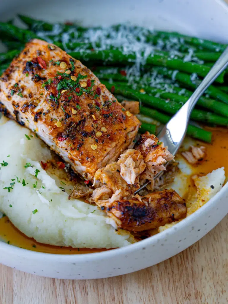 Close-up of baked lemon butter salmon flaked with a fork.