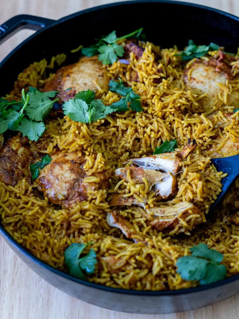 One-pan Tandoori Chicken and Rice – spiced chicken and fragrant rice in a pan, garnished with fresh coriander and served with a spoon