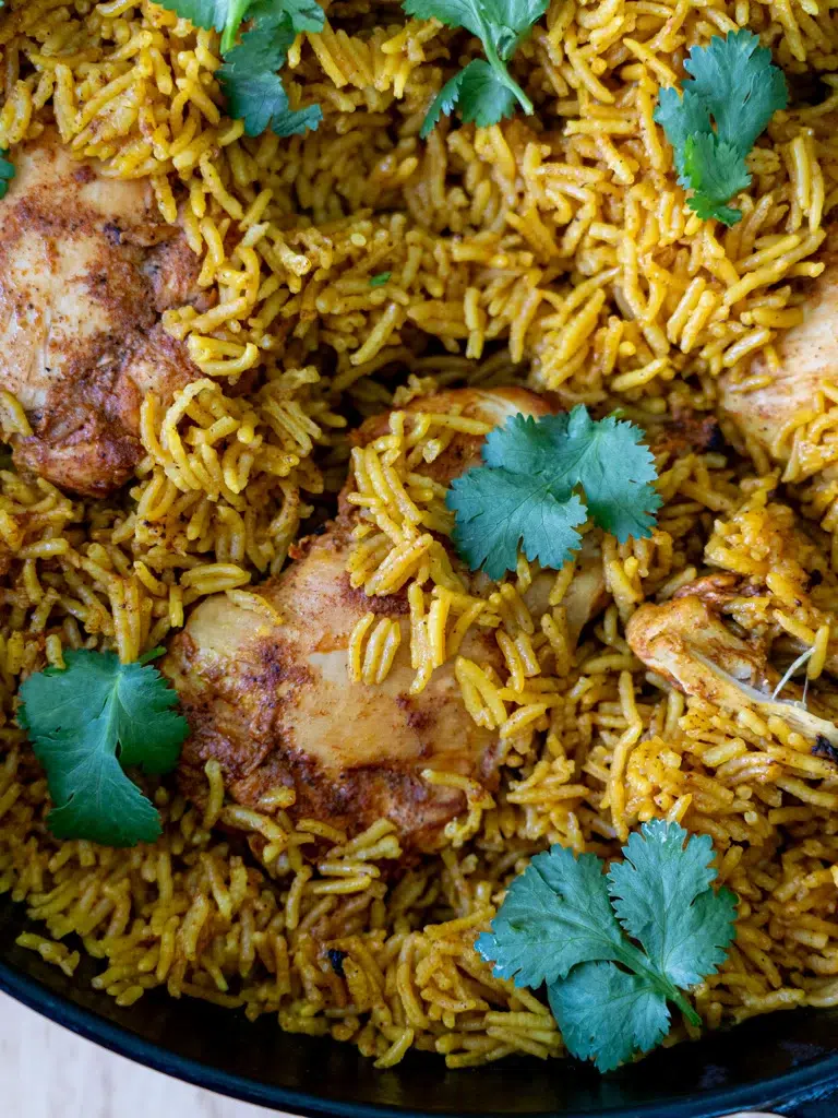 Close-up of One-pan Tandoori Chicken and Rice fresh out of the oven, with golden spiced chicken nestled in fragrant rice