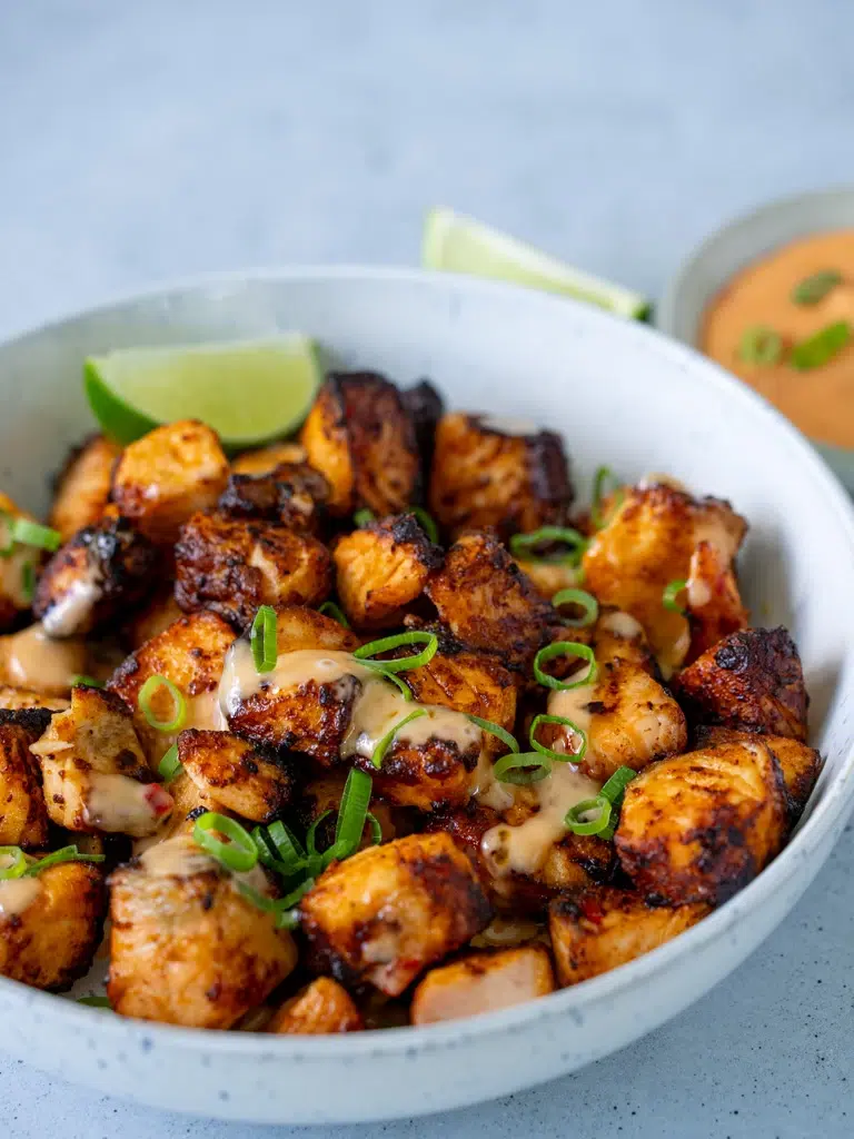 Sideways view of a Bang Bang salmon platter, arranged neatly and drizzled with creamy sauce, ready to serve.