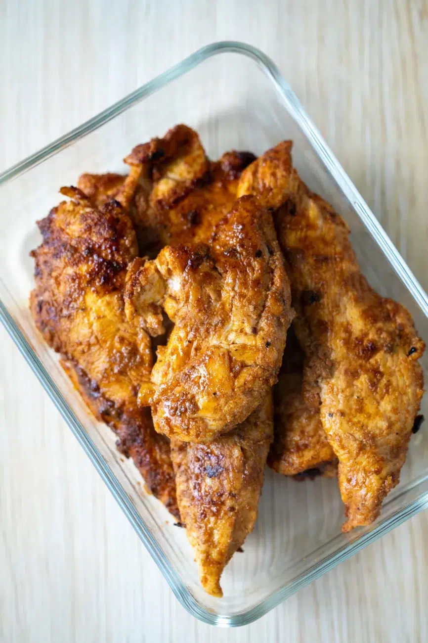 Close-up of cooked Portuguese-style chili chicken fillets in a glass container