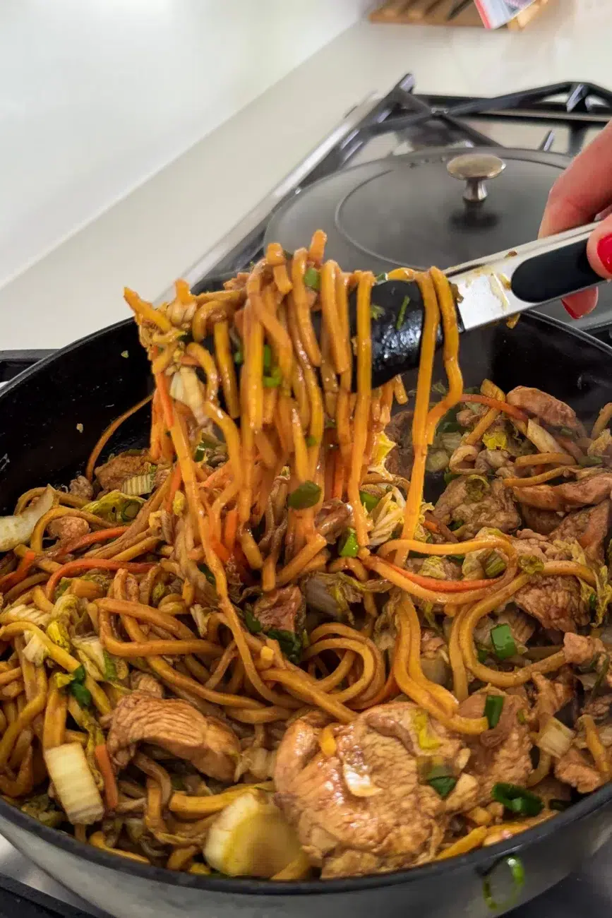 Noodles stretched out of the pan with tongs