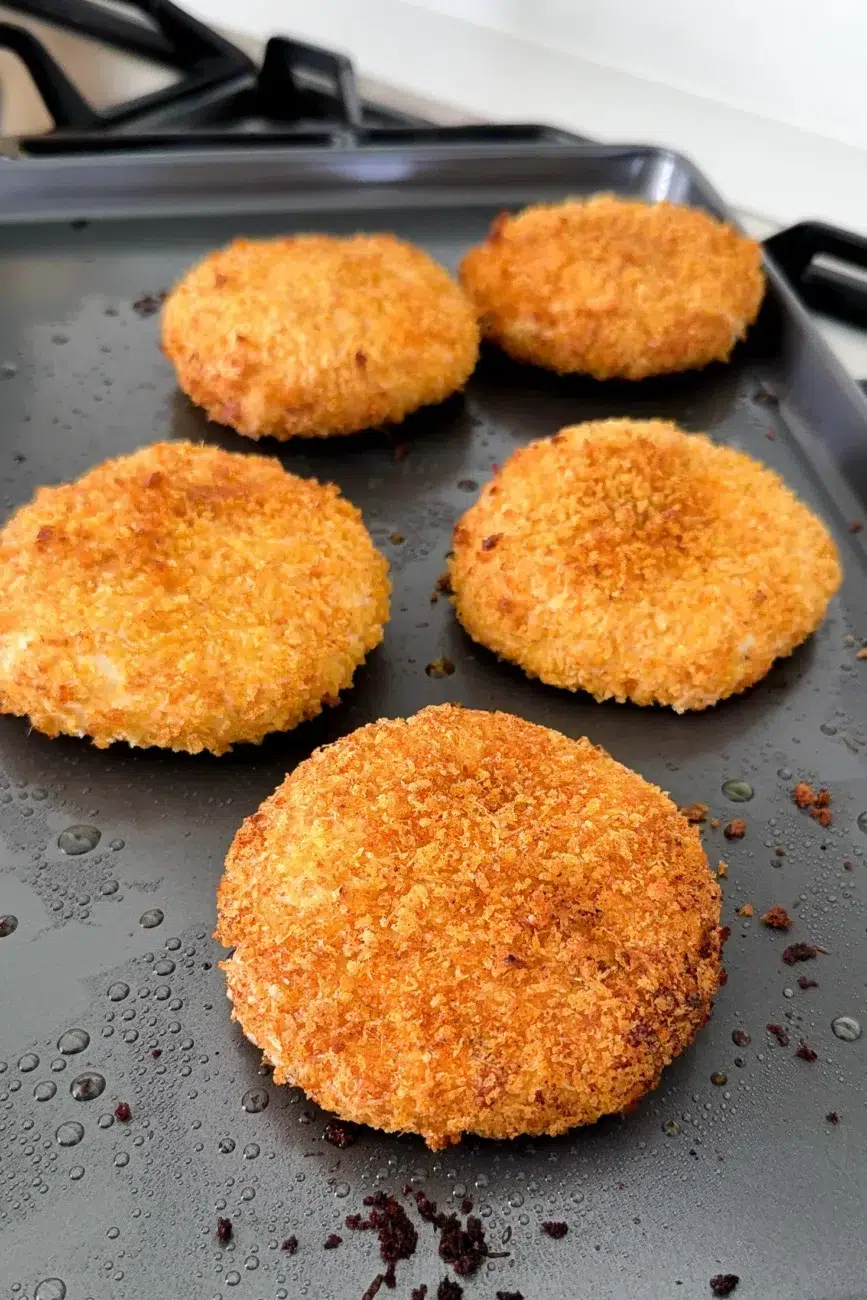 Crispy baked chicken burger patties on metal baking tray