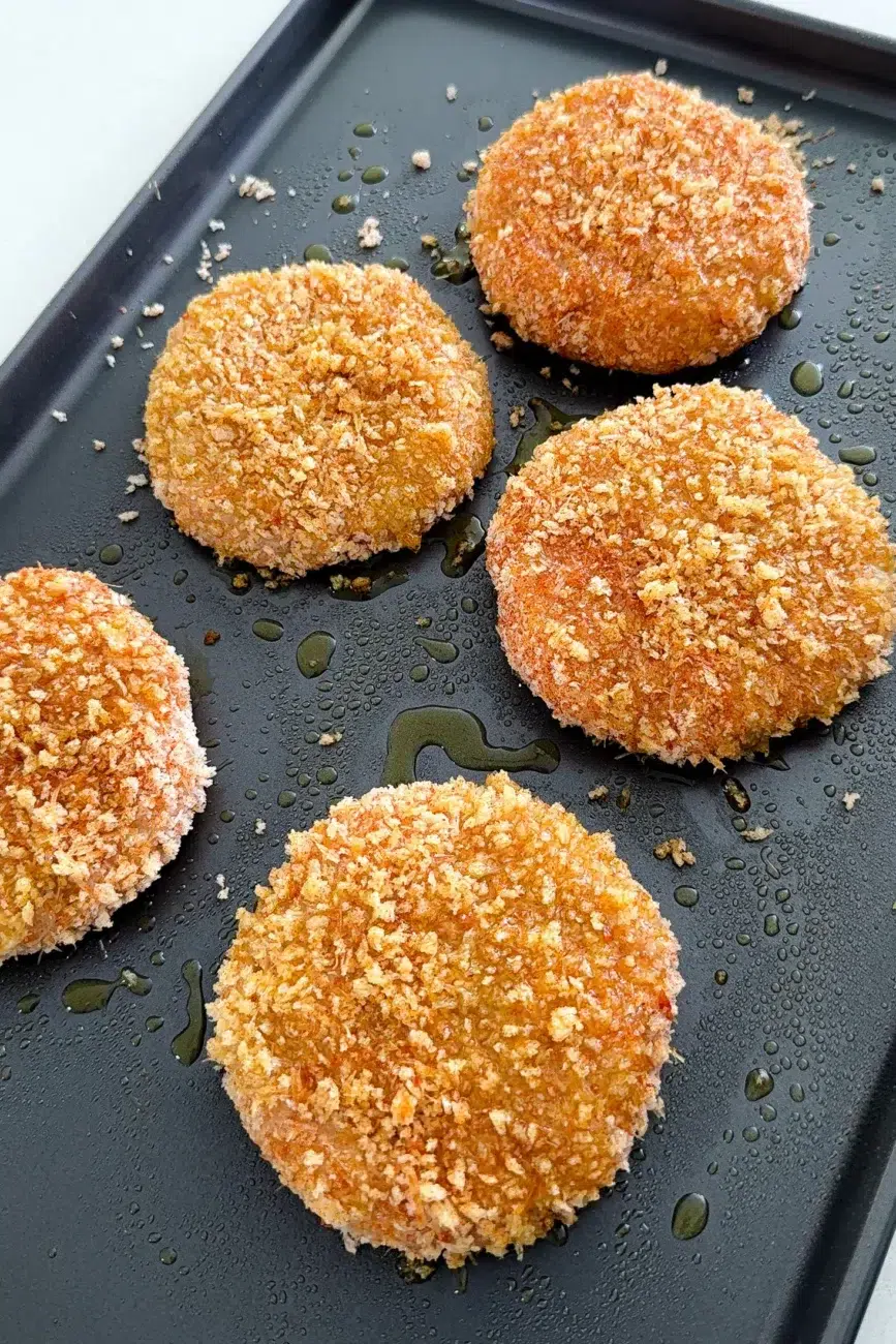 Crumbed chicken burger patties sprayed with olive oil before baking