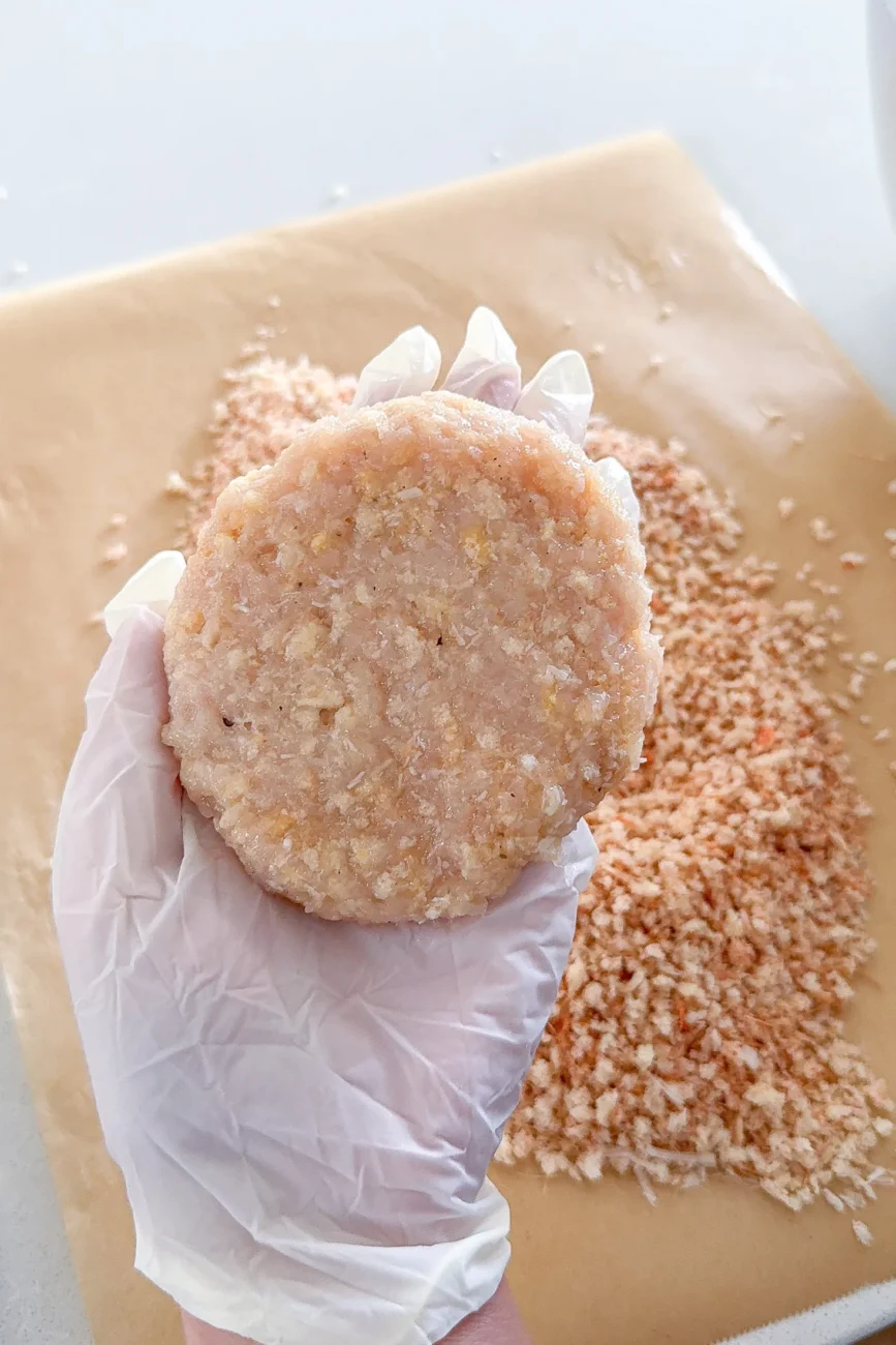 Raw chicken burger patty shaped and ready for crumbing